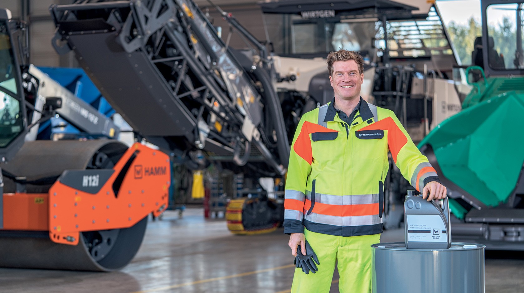 Table with laptop, coffee mug and writing utensils Window with view over the machine workshop in the background